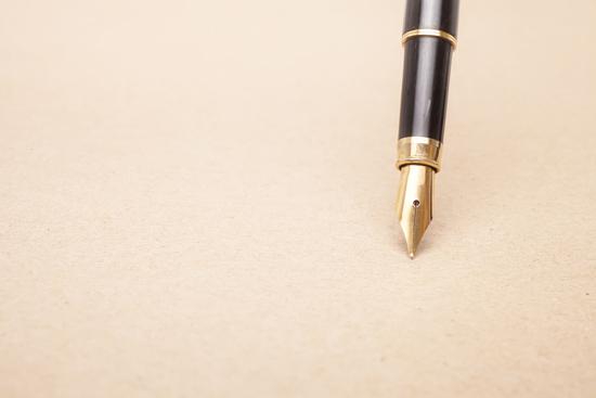 Füllfederhalter mit goldener Spitze auf braunem Papier.